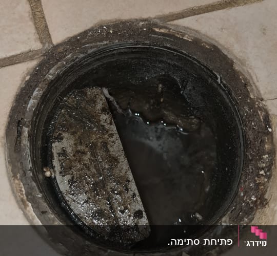קופסת ביקורת פתוחה ברצפה עם מים עומדים במהלך פתיחת סתימה